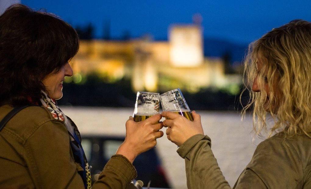 Mujeres brindando con la Alhambra de fondo.