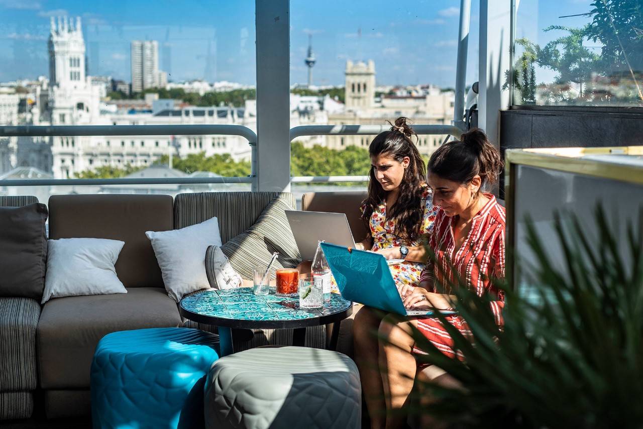 Dos chicas teletrabajan con sus ordenadores en la terraza de Casa Suecia.