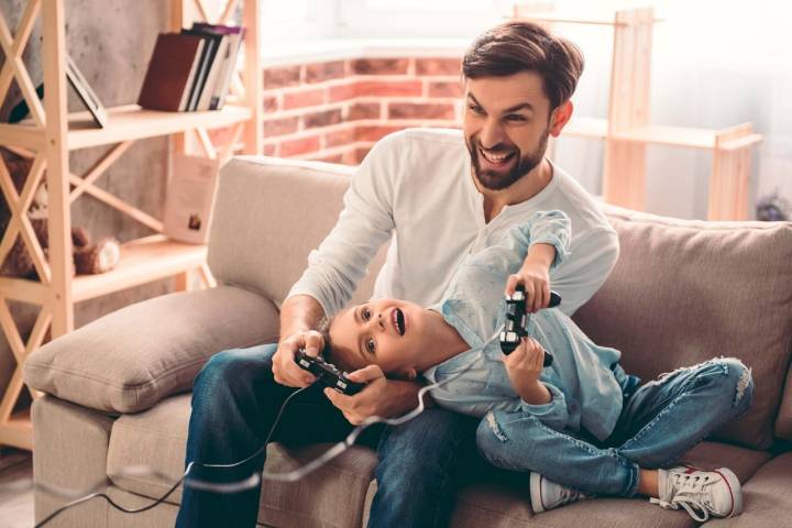 Un padre y un hijo juegan con videojuegos.