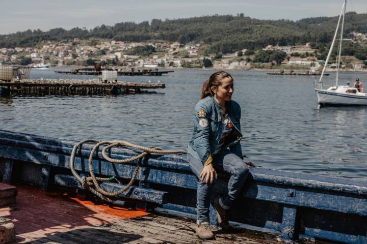 La periodista motera sobre una de las barcas con las bateas tras de sí y, al fondo, Combarro.