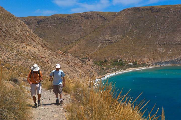 Dos hombres caminan cerca de la cala San Pedro.