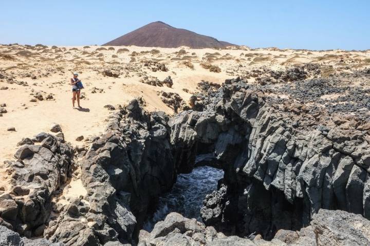 Parte del monumento natural de Los Caletones con un volcán al fondo.